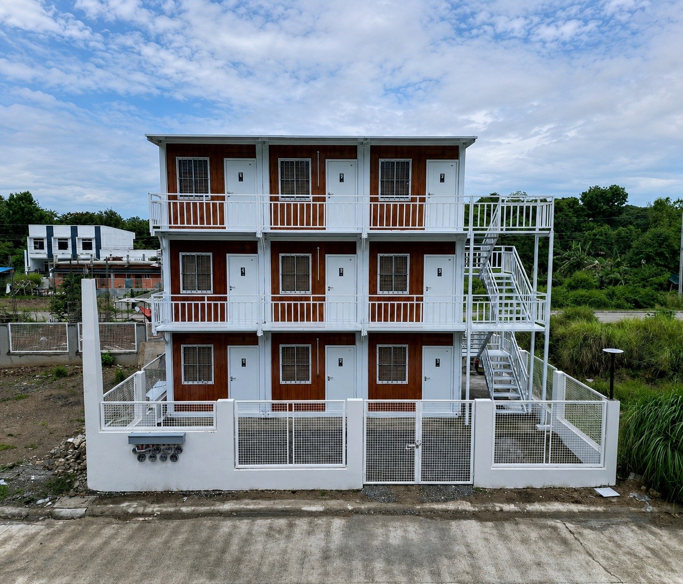 Three-storey container accommodation building with wood-look cladding and exterior stairs