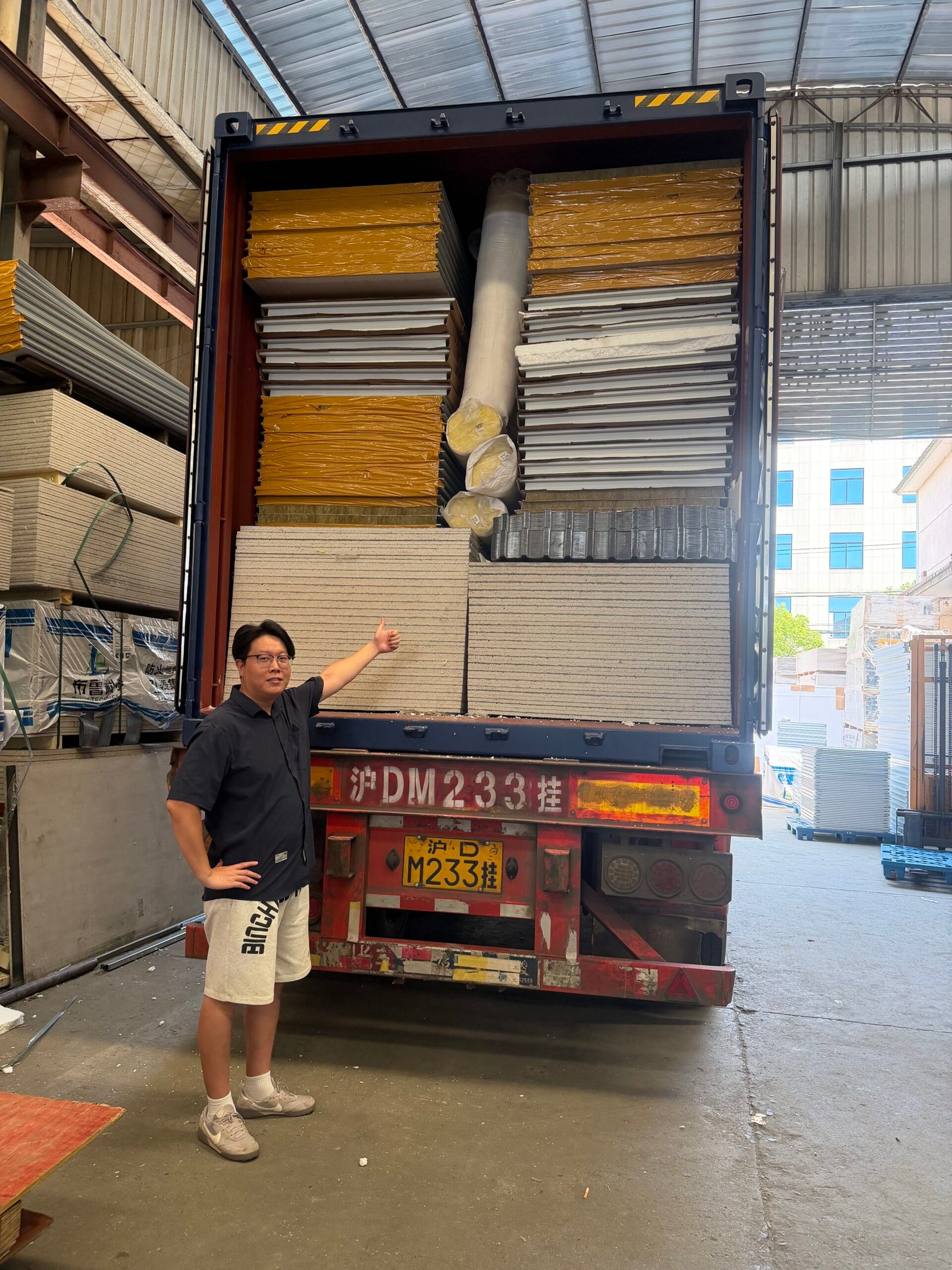 Shipping container loaded with stacked flat pack house panels, steel components and insulation rolls